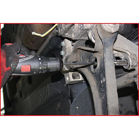 Person verschraubt mit einer Bohrmaschine einen Fahrzeugteil. Nahaufnahme der Reparatur.